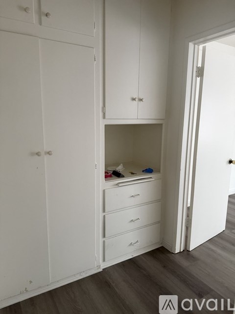 A white wardrobe with a mirror above the drawers is open.
