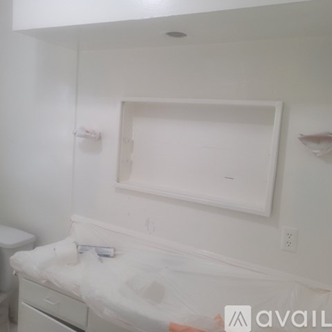 A white changing table with a white cabinet and a white toilet in the corner.