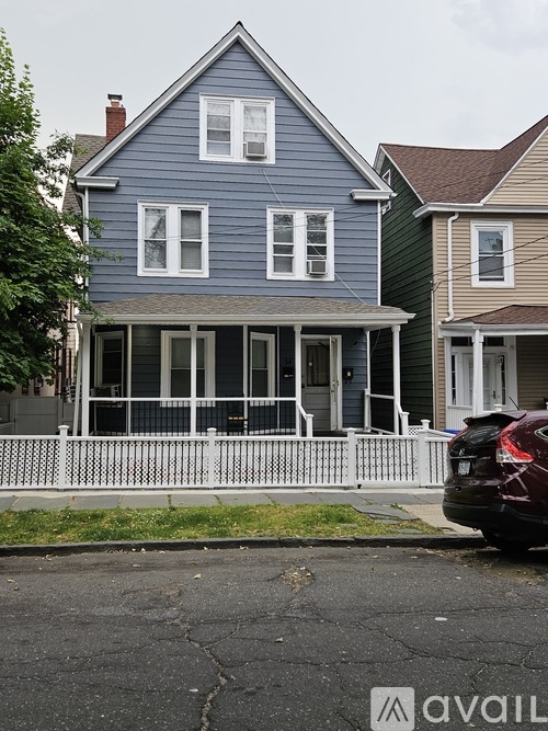 A blue house with a white fence and a car parked in front.