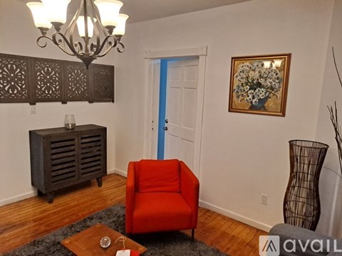 A living room with a red chair and a chandelier.
