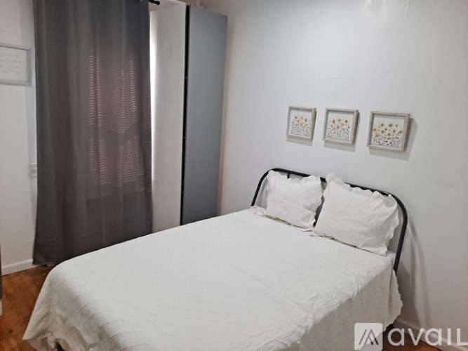 A bedroom with a white bed and a grey curtain.