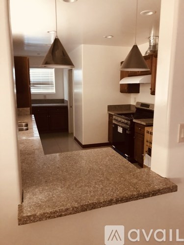 A kitchen with granite countertops and a white wall.