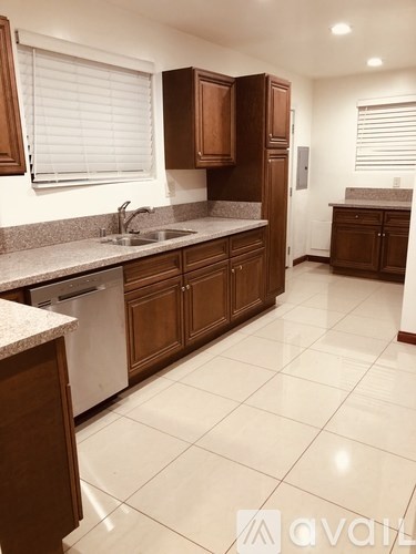A kitchen with brown cabinets and a white sink.