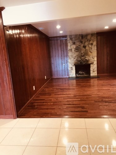 A room with wooden floors and a stone wall with a fireplace.