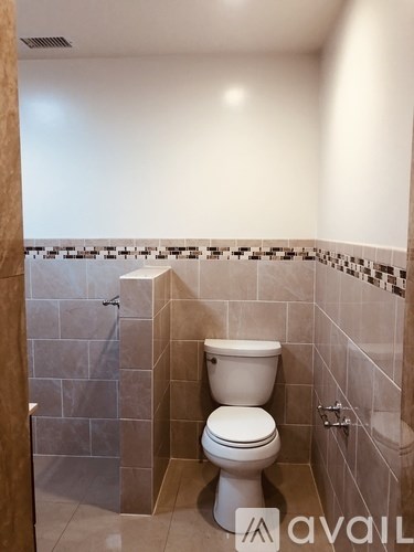 A white toilet in a bathroom with a tiled shower area.