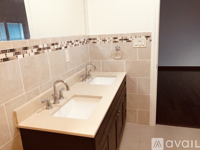 A bathroom with a double sink vanity and a mirror above it.