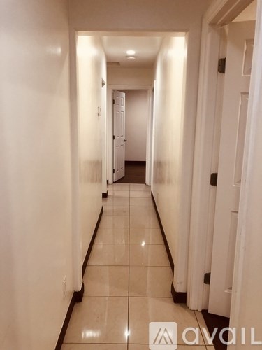 A long hallway with white walls and tile flooring.