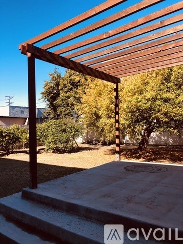 A wooden pergola over a concrete patio.