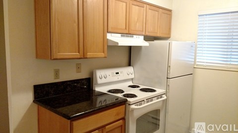 A kitchen with a white stove and a white refrigerator.