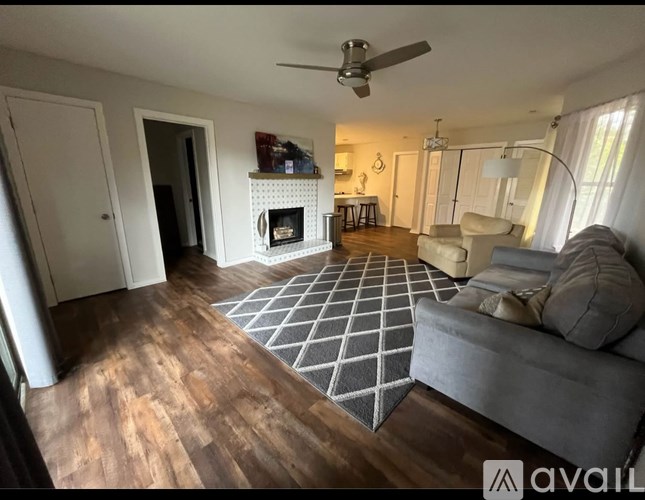 A living room with a fireplace and a grey couch.