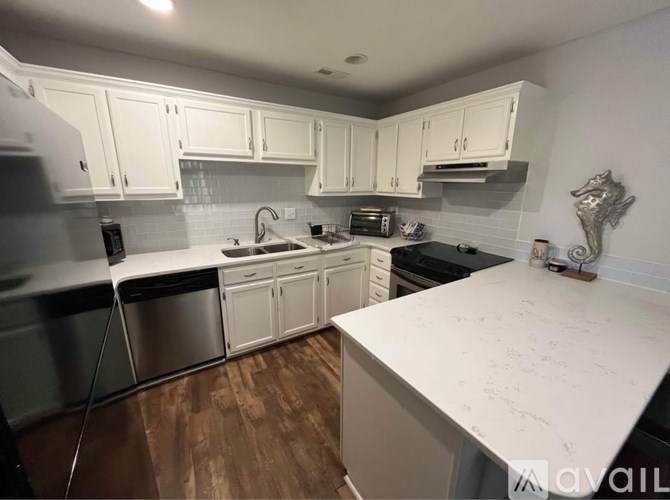 A kitchen with white cabinets and a wooden floor.