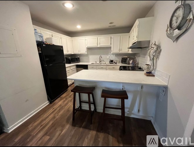 A kitchen with white cabinets and a black refrigerator.