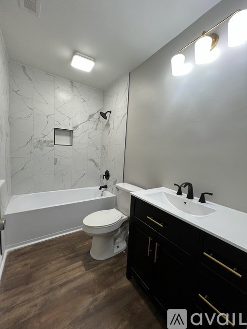 A bathroom with a white toilet, a white bathtub, and a white sink with black cabinets.