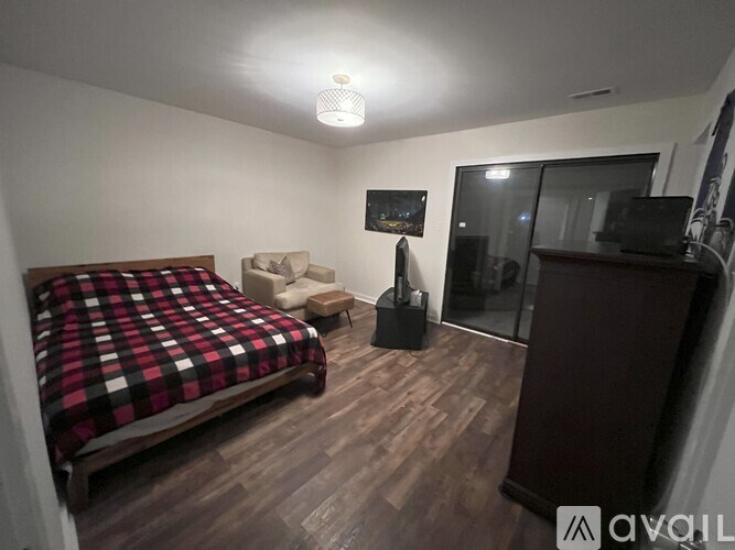 A bedroom with a bed, chair, and a cabinet.