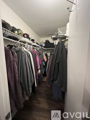 A white closet with clothes hanging on shelves.