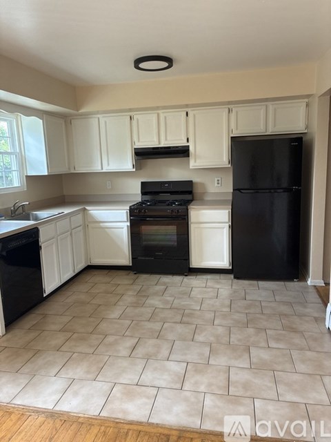 A kitchen with black appliances and white cabinets.