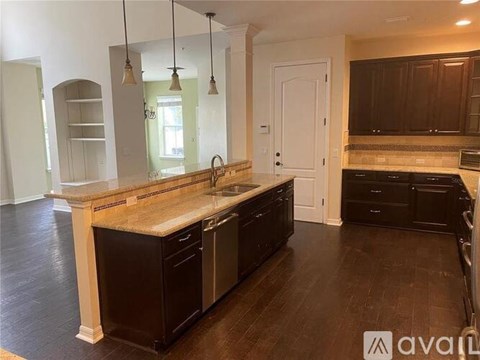A kitchen with dark wood cabinets and a granite countertop.