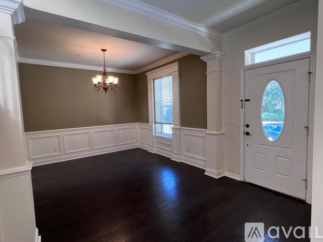 A room with a chandelier, a window with blinds, and a door with a window in the middle.