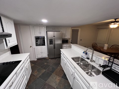A kitchen with white cabinets and a tile floor.