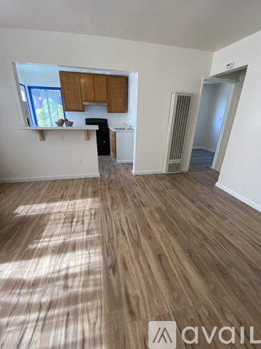 A room with wooden flooring and a window with brown cabinets.