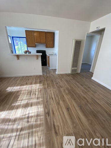 A room with wooden flooring and a window with brown cabinets.