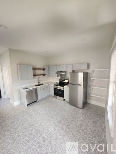 A kitchen with white appliances and a patterned carpet.