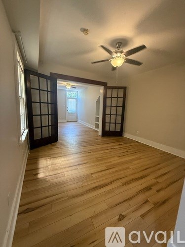 A white two-story house with black shutters and a black trash can in front.