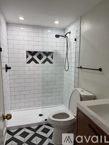 A bathroom with a toilet, sink, and a shower with a black and white tile floor.