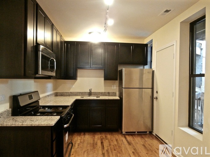 A kitchen with black cabinets and a stainless steel refrigerator.