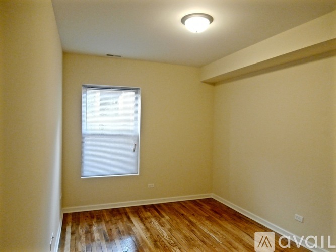 A room with wooden flooring and a window with blinds.
