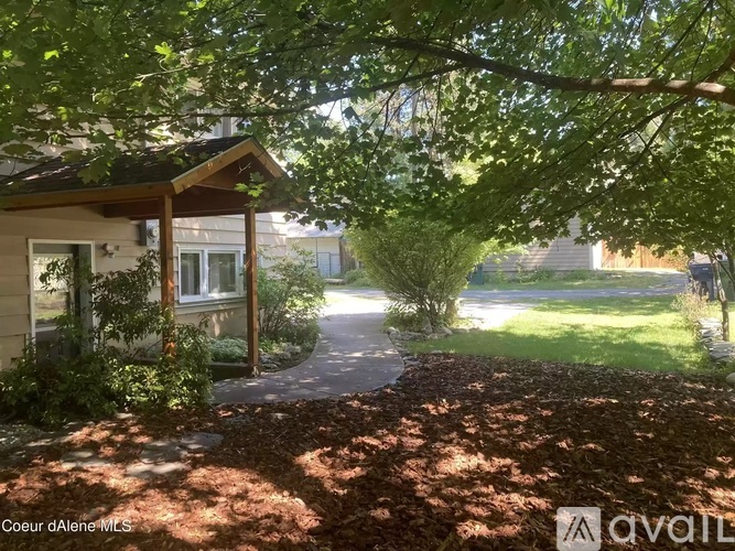 A house with a porch and a tree in front of it.