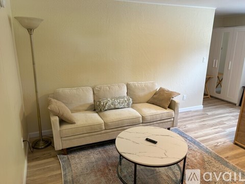 A living room with a beige couch and a round table.