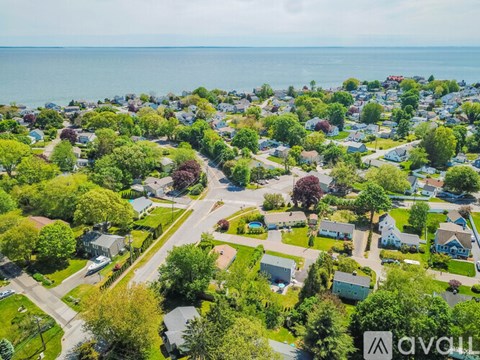 A bird's eye view of a residential area with houses, trees, and a road.