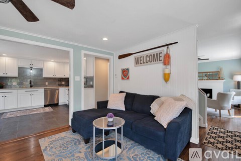A living room with a blue couch and a white wall with a "Welcome" sign.