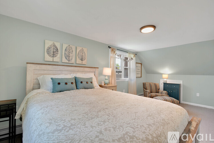 A bedroom with a large bed and a chair.