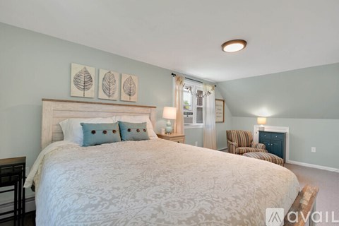 A bedroom with a large bed and a chair.