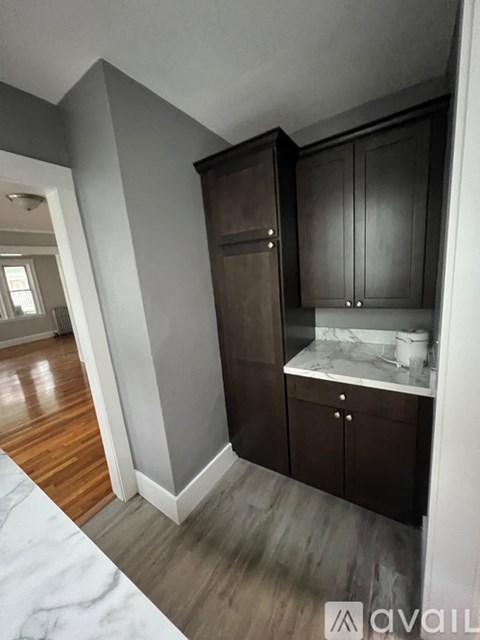 A kitchen with dark wood cabinets and a marble countertop.