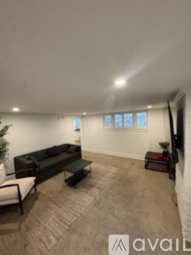 A living room with a black couch and a white chair.