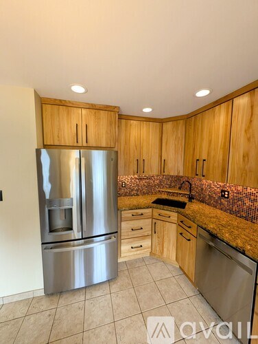 A kitchen with a stainless steel refrigerator and wooden cabinets.