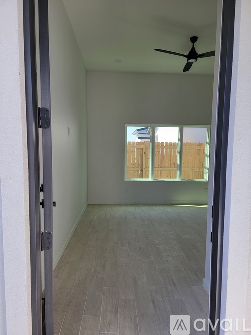 A room with a ceiling fan and sliding glass doors.