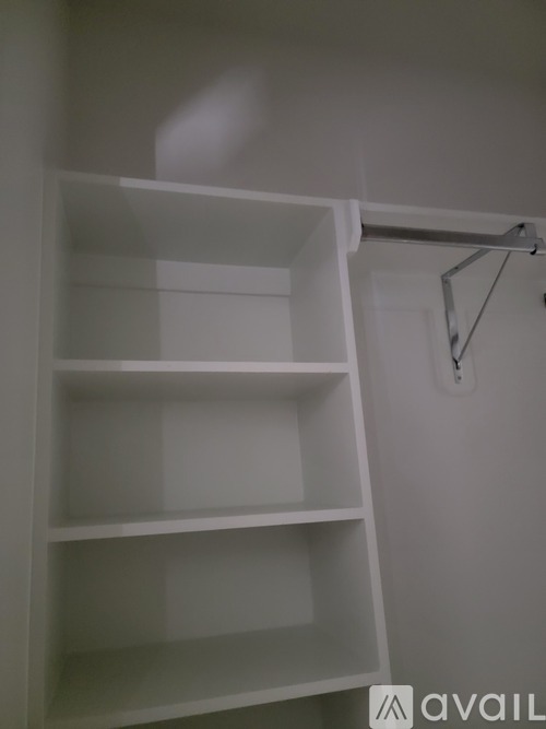A white shelving unit with four shelves is mounted on a white wall.