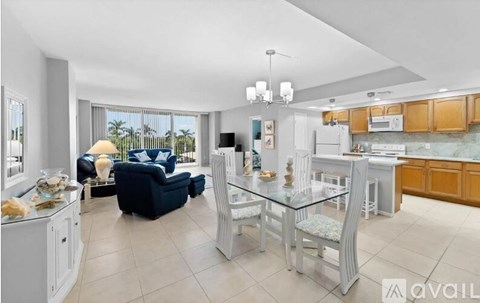 A well-lit kitchen and living room with modern furniture and appliances.