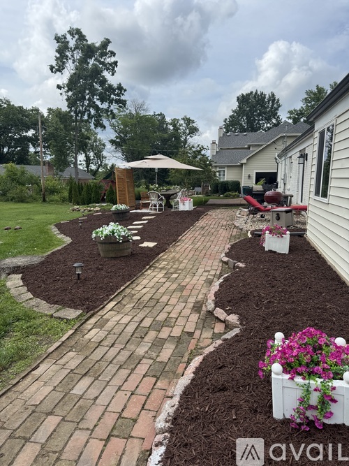 A backyard with a brick walkway and white planters.