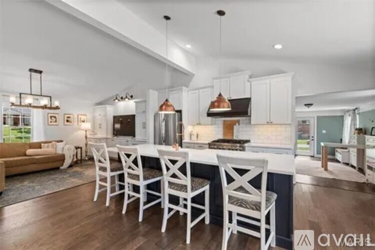 A modern kitchen with white chairs and a central island.