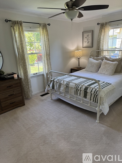 A bedroom with a white bed and a ceiling fan.