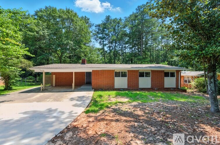 A red brick house with a white garage door is surrounded by greenery.