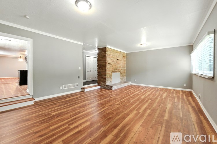 A room with wooden flooring and a brick pillar in the corner.
