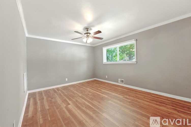 A room with wooden flooring and a ceiling fan.