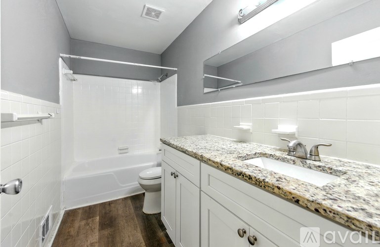 A bathroom with a white tub, sink, and toilet.