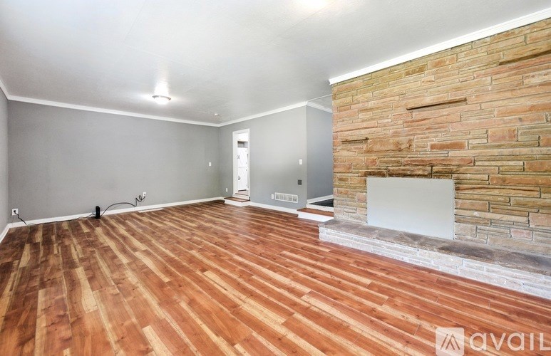 A room with wooden flooring and a brick wall.